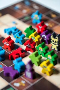 Custom board game pieces including meeples, miniatures, dice, acrylic tokens and metal game components